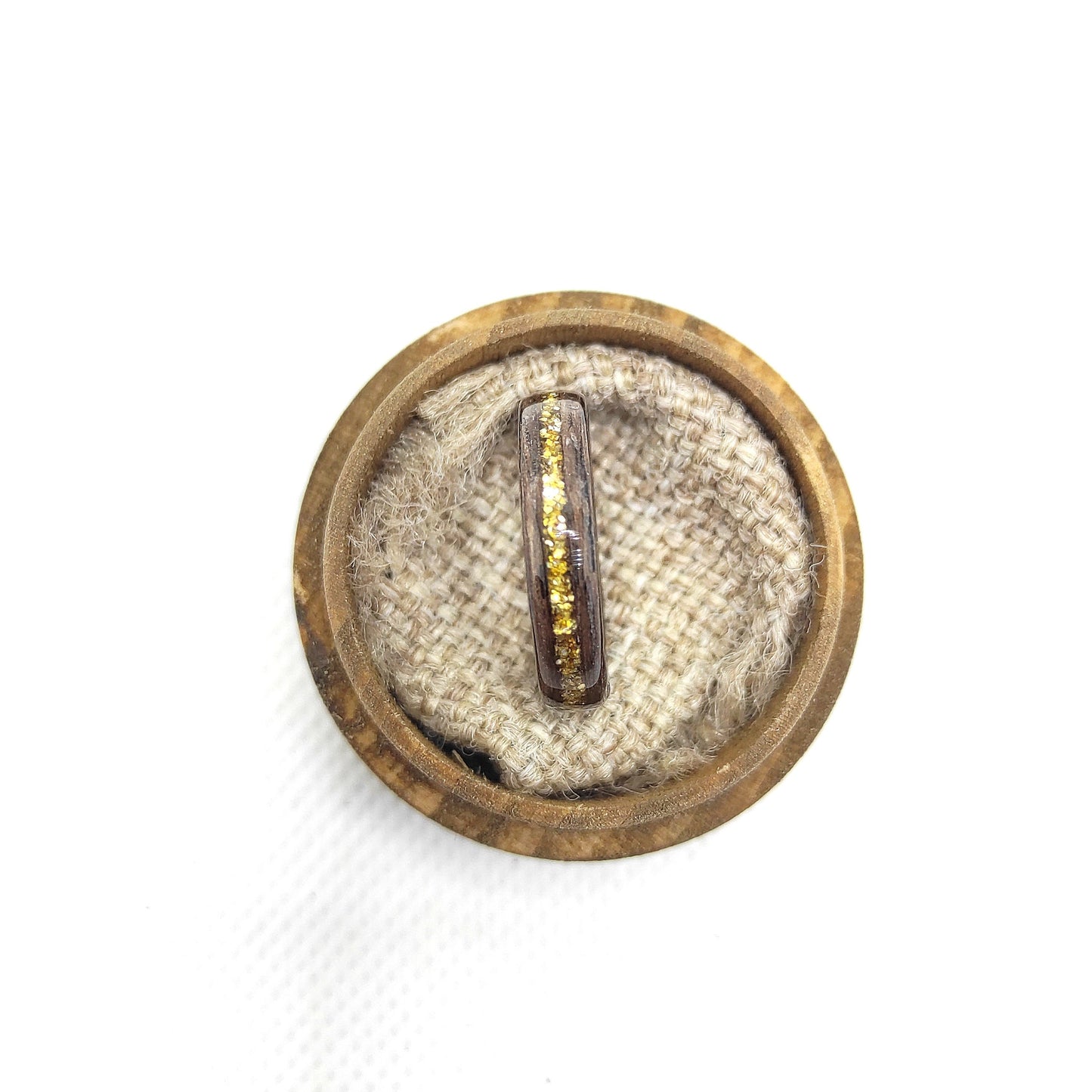 Handmade walnut wood ring with gold glitter inlay on a wooden surface