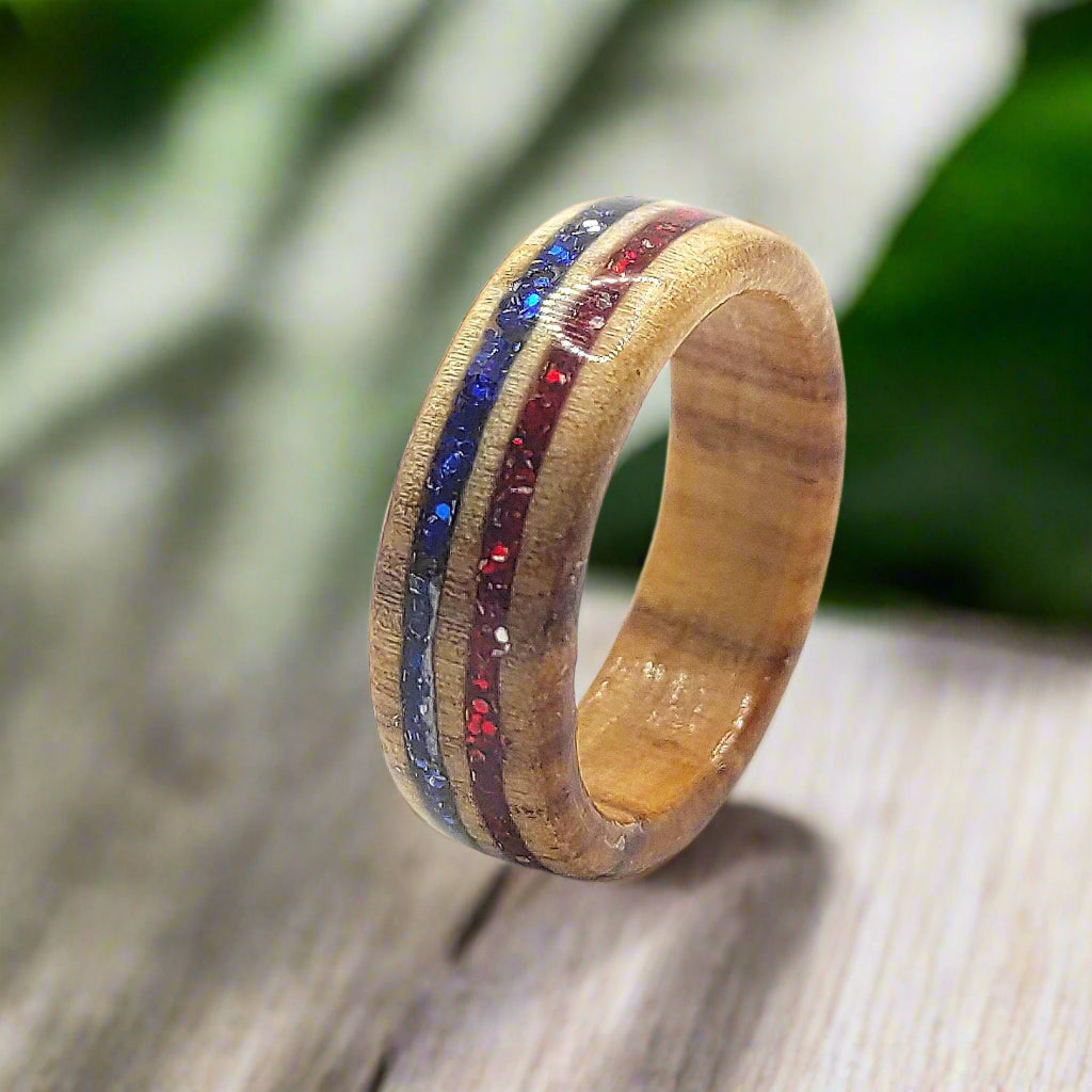 Close-up of handmade willow wood ring with red and blue glitter inlay