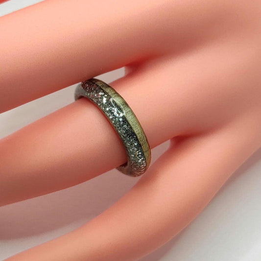 Close-up of handmade willow wood ring with silver glitter inlay on a white background

