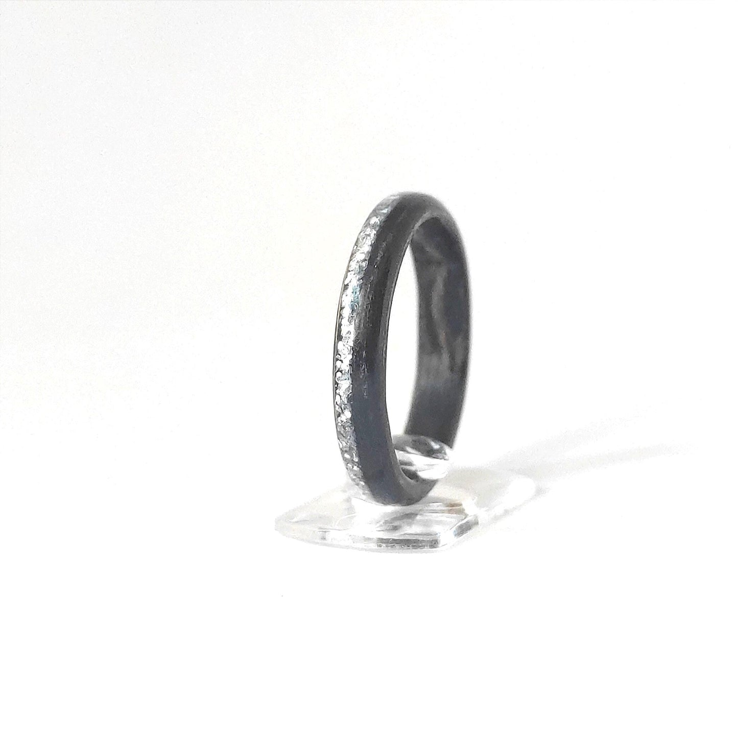 Close-up of ebony wood grain and silver glitter channel on handcrafted ring