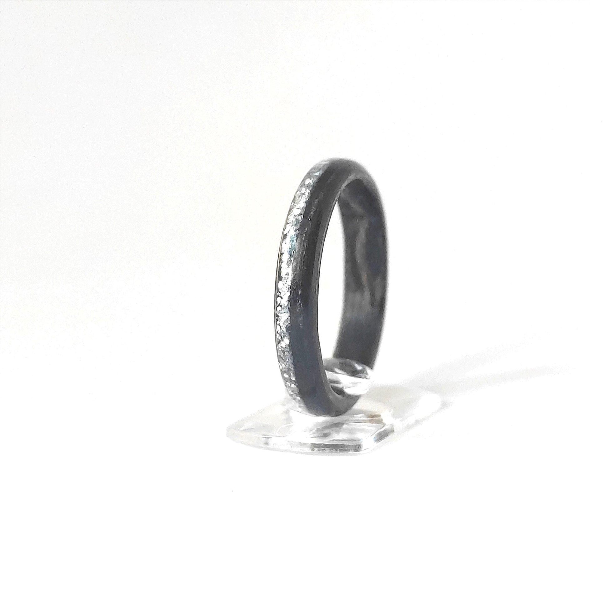 Close-up of ebony wood grain and silver glitter channel on handcrafted ring