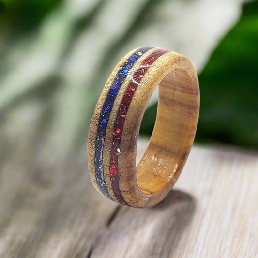 Close-up of handmade willow wood ring with red and blue glitter inlay